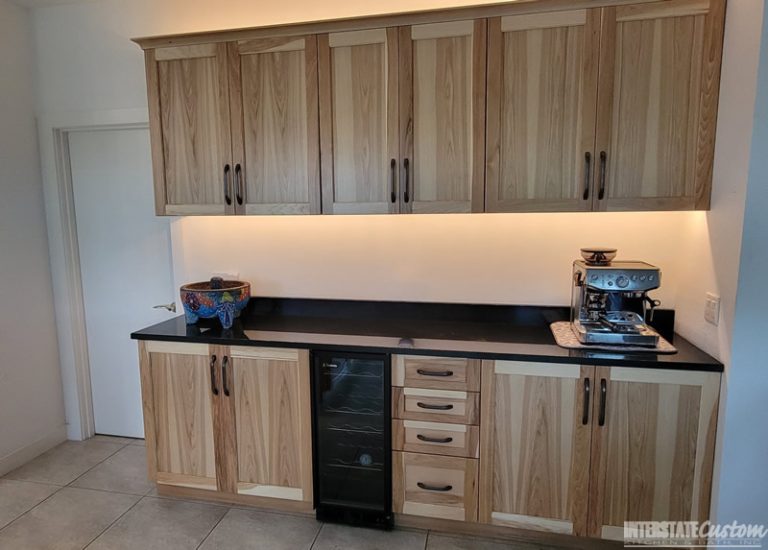 Modern kitchen with cabinet refacing featuring Natural Hickory wood cabinetry, black rustic hardware, black granite countertops, a large central island with a prep sink, and stainless steel appliances. Project by Interstate Custom Kitchen & Bath, Inc."