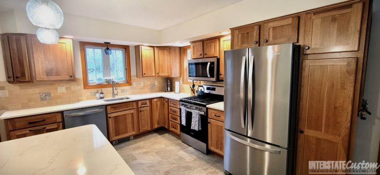 Eat-in Country Kitchen remodel featuring Hickory Harvest shaker door cabinetry, Spectrum Indulgence Quartz countertops, large peninsula, pendant lighting, and stainless steel appliances. Project by Interstate Custom Kitchen & Bath, Inc.