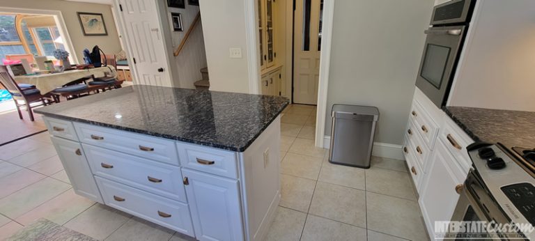 Another angle of the traditional kitchen remodel, displaying the combination of white painted raised panel cabinets, sapphire blue granite countertops, natural stone tile backsplash, and stainless steel appliances. Project by Interstate Custom Kitchen & Bath, Inc.