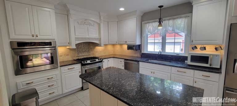 Full view of the traditional kitchen remodel, highlighting the stainless steel appliances, white painted raised panel cabinets, sapphire blue granite countertops, and natural stone tile backsplash. Project by Interstate Custom Kitchen & Bath, Inc.