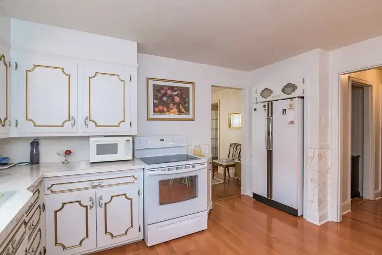Before kitchen with white raised panel cabinets, laminate countertops, and hardwood floors in Longmeadow MA
