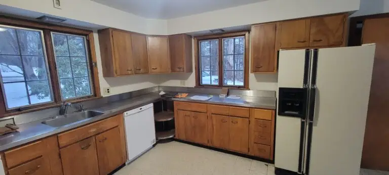 Original kitchen with wood cabinetry, laminate counters, corner shelving, and white appliances