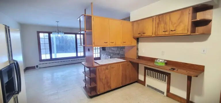 Old kitchen layout with wood cabinets, built-in desk area, and open view to adjacent room