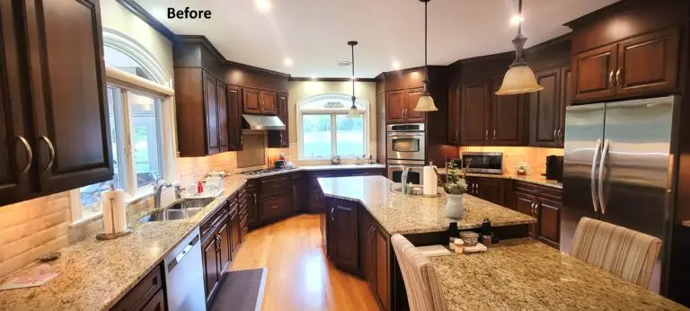 Before kitchen renovation showing dark cabinetry, granite island, pendant lighting, and hardwood floors in traditional layout