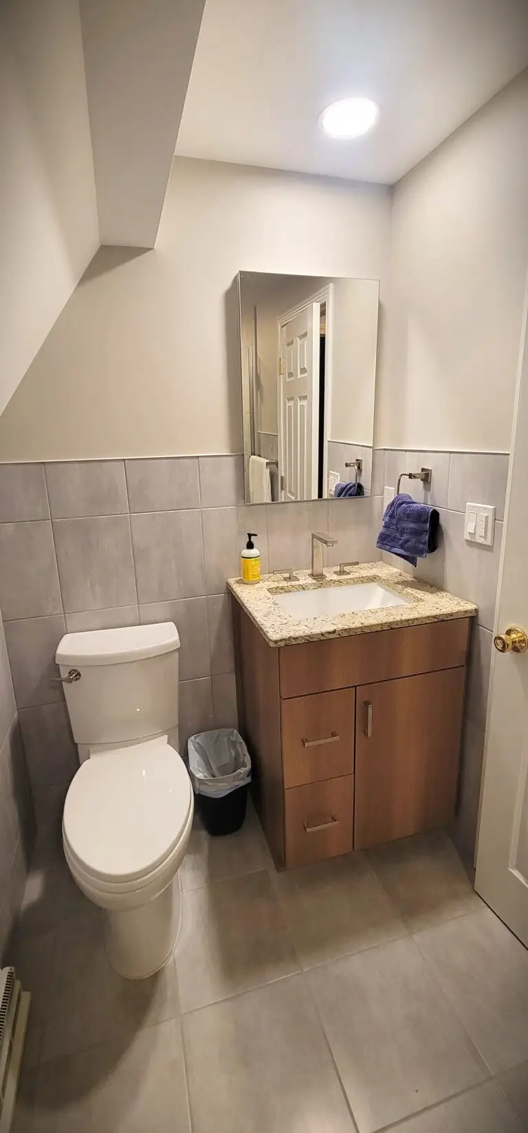 Bathroom upgrade featuring compact vanity, granite countertop, and neutral tile flooring