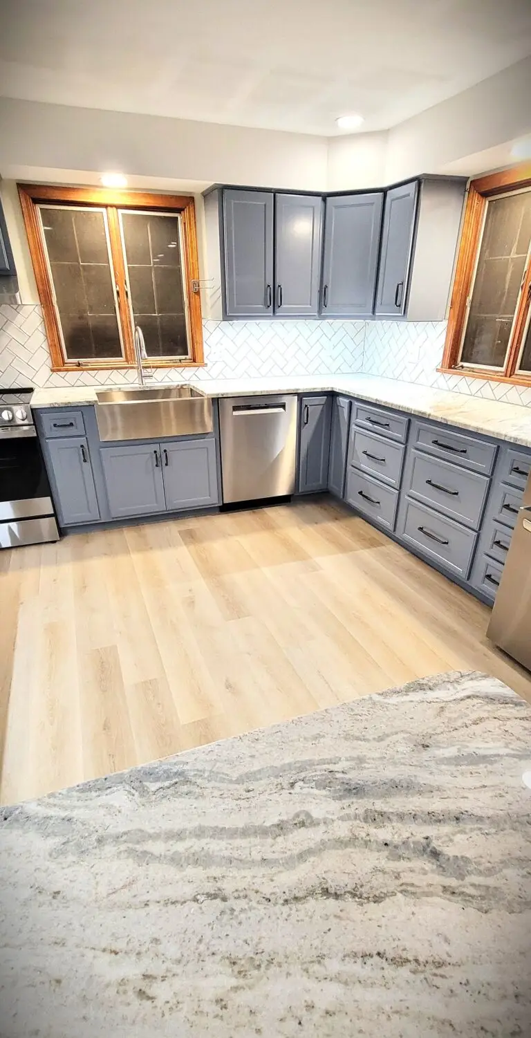 Updated kitchen with gray cabinetry, farmhouse sink, quartz counters, and herringbone tile backsplash
