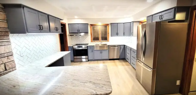 Open concept kitchen with peninsula seating, gray cabinetry, stone accent wall, and recessed lighting