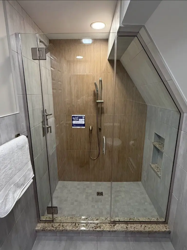 Custom walk-in shower with glass enclosure, vertical accent tile, and recessed storage niches